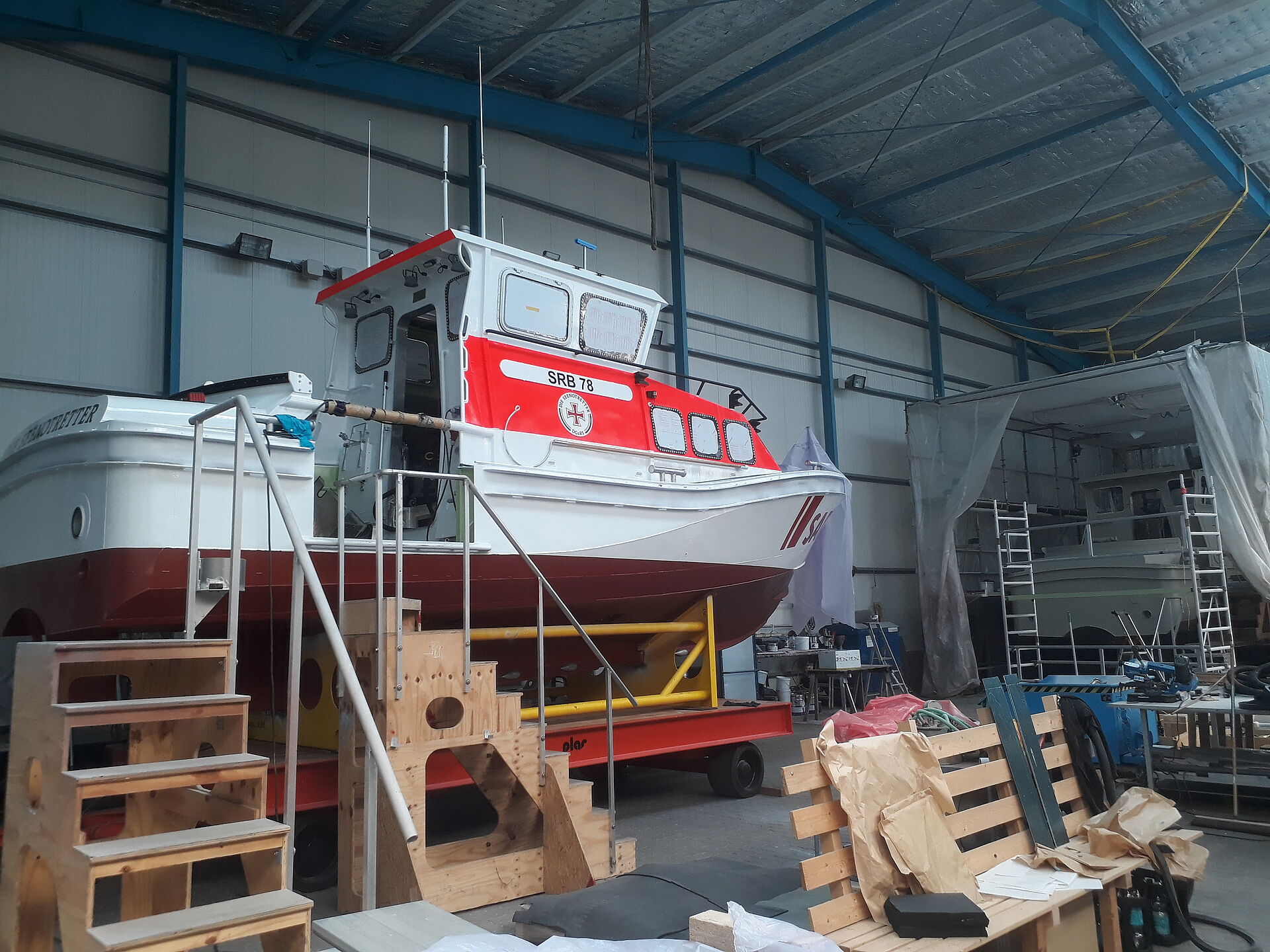 In einer hellen Werfthalle liegt ein fertig lackiertes Seenotrettungsboot.