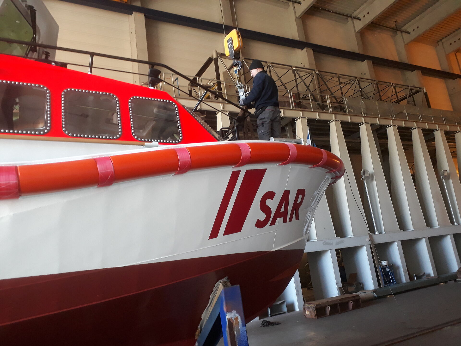 Ein Werftmitarbeiter steht in der Werfthalle auf dem Vorschiff des neuen Seenotrettungsbootes.